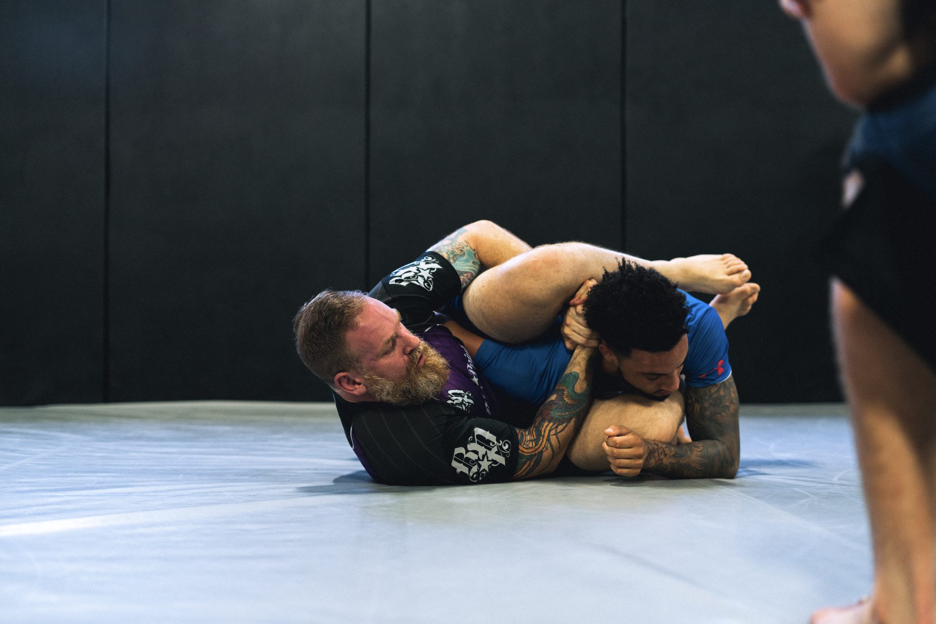 A coach controlling a student from guard during live rounds on the Cromwell mat