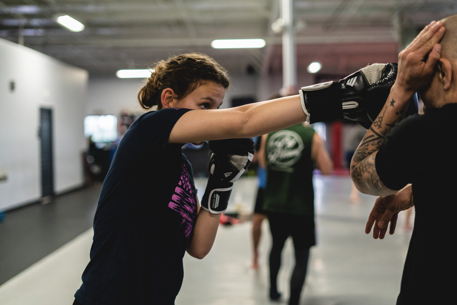 A gloved straight punch landing at full extension on a coach's focus mitt