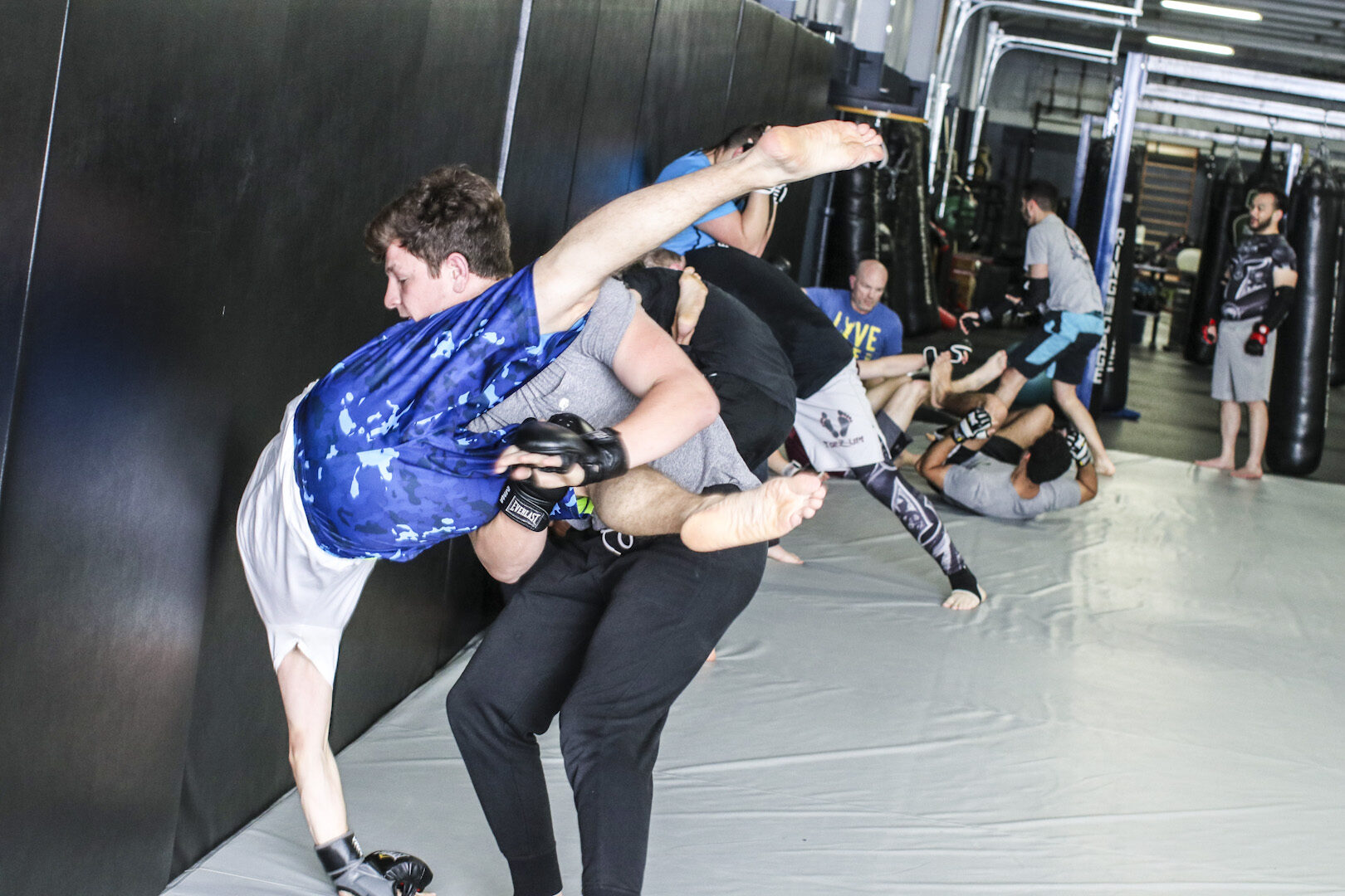 A throw going up against the wall pad, shot from mat side