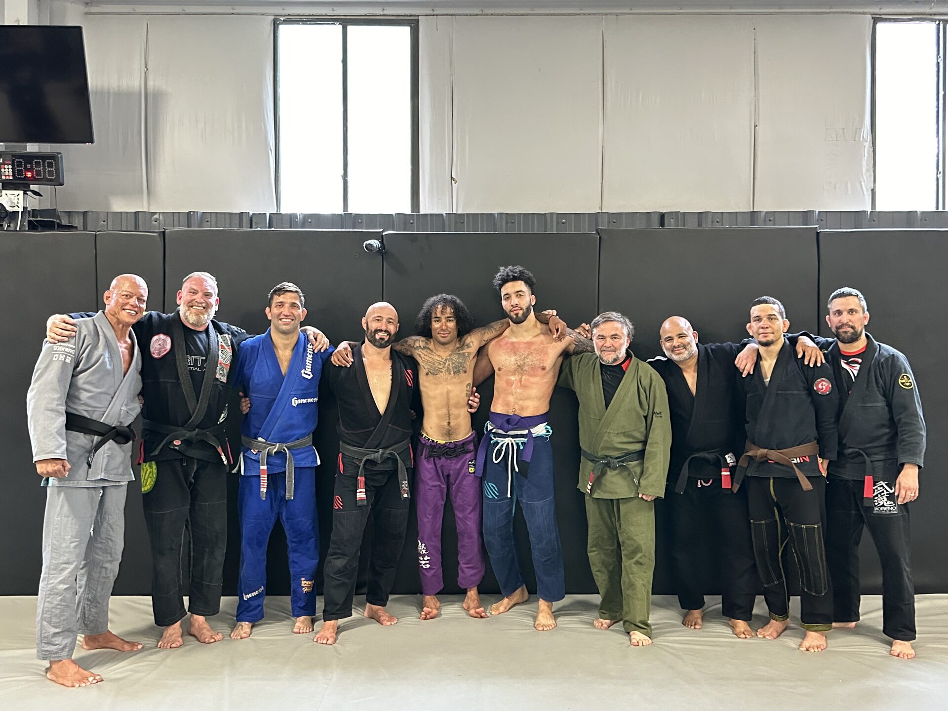 Eleven TRITAC members standing arm in arm along the wall padding at the gym in Cromwell