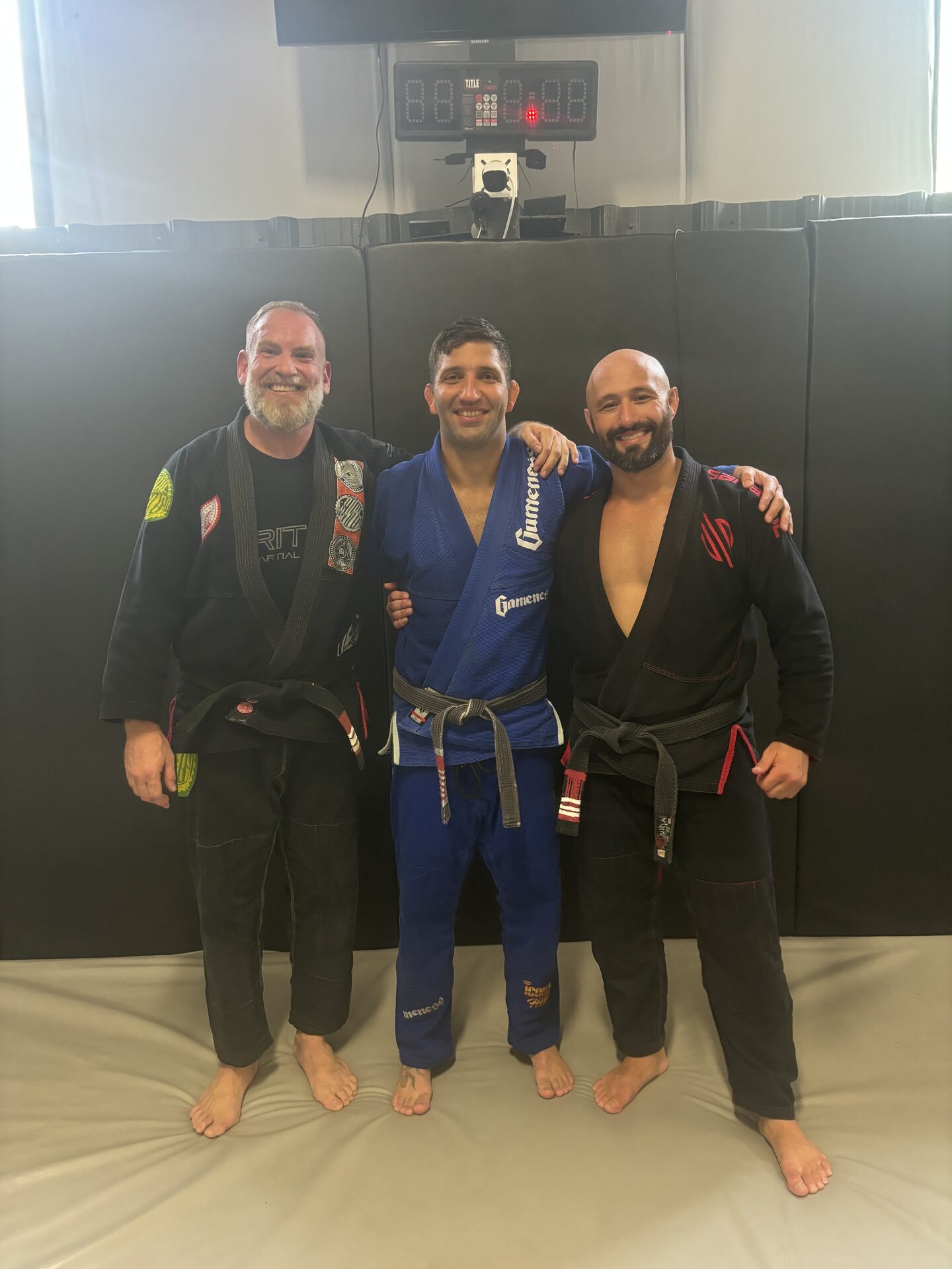 Instructors standing together on the mat in gis, their belts visible